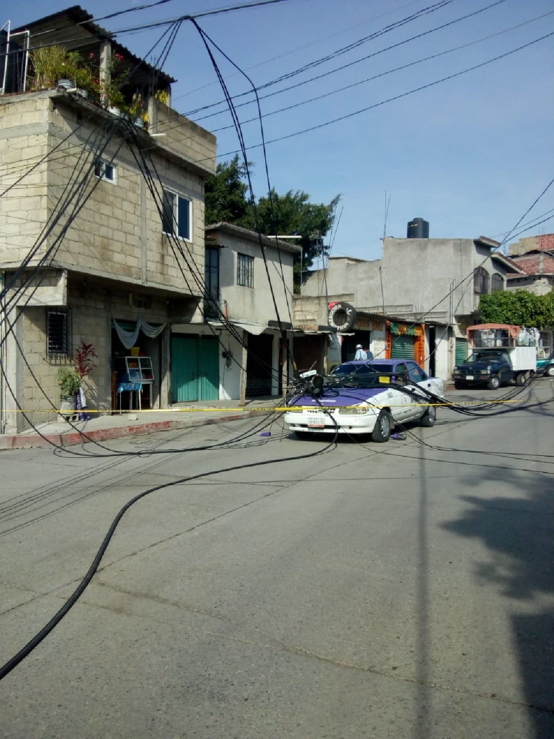 Cae poste telefónico sobre un taxi